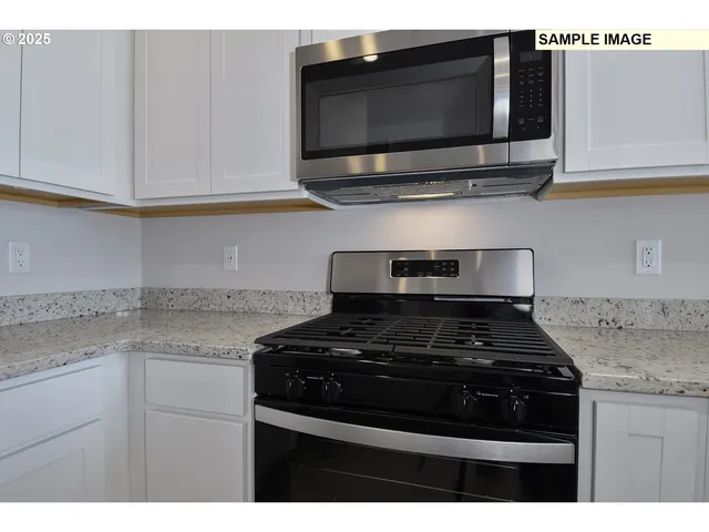 a kitchen with stainless steel appliances granite countertop white cabinets stove top oven and granite counter top
