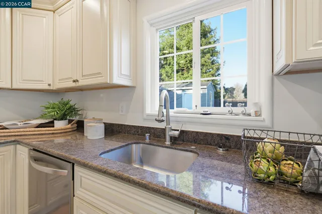 a kitchen with granite countertop a sink and a white wooden cabinets