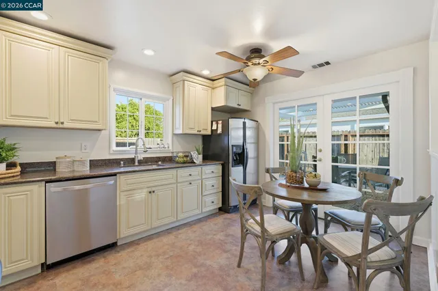 a kitchen with stainless steel appliances granite countertop a stove a sink dishwasher a dining table and chairs with wooden floor