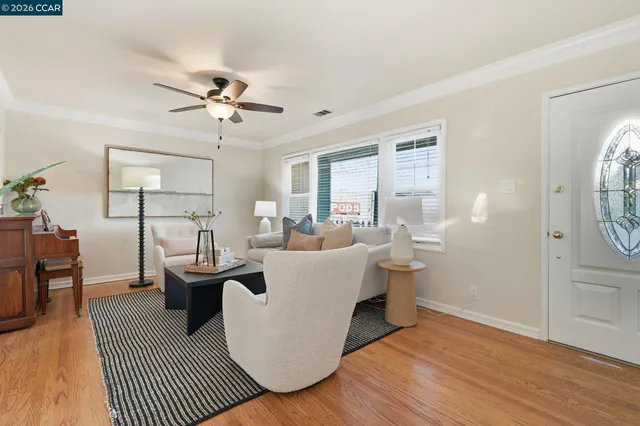 a living room with furniture a large window and wooden floor