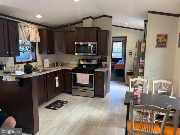 a kitchen with kitchen island granite countertop a sink dishwasher stove and cabinets