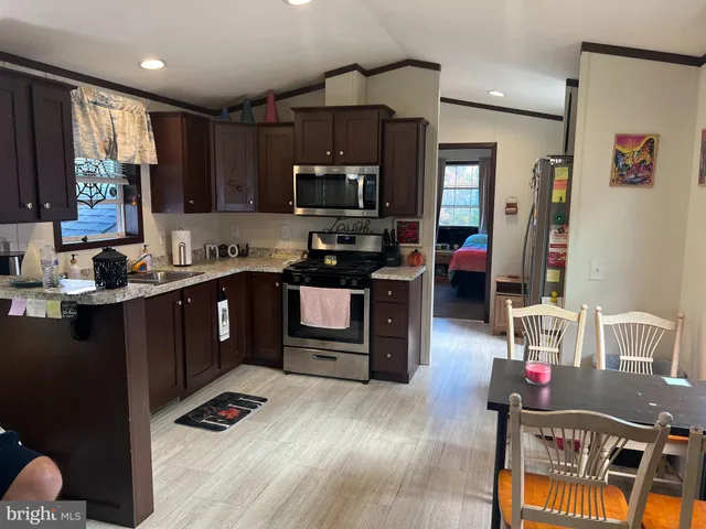 a kitchen with kitchen island granite countertop a sink dishwasher stove and cabinets