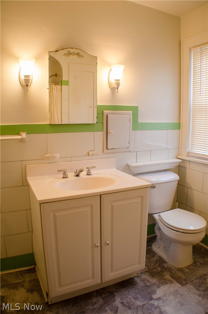 1123 Berwin Street Akron, OH 44310 - Photo 23 of 34 Updated vanity with cultured marble counter top, original ceramic sconces, Beautiful white with green trim Vitrolite tiles still on place & updated efficient low flow toilet.