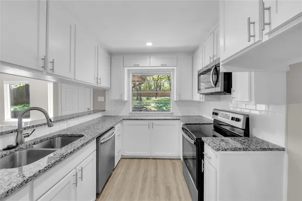 a kitchen with granite countertop a sink stove and cabinets
