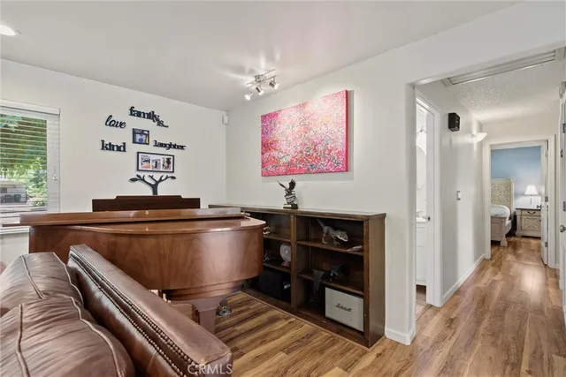 a living room with a piano and wooden floor