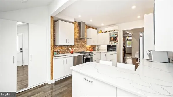 a large white kitchen with stainless steel appliances kitchen island granite countertop a refrigerator and cabinets