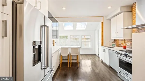 a kitchen with stainless steel appliances a stove a refrigerator and wooden floor