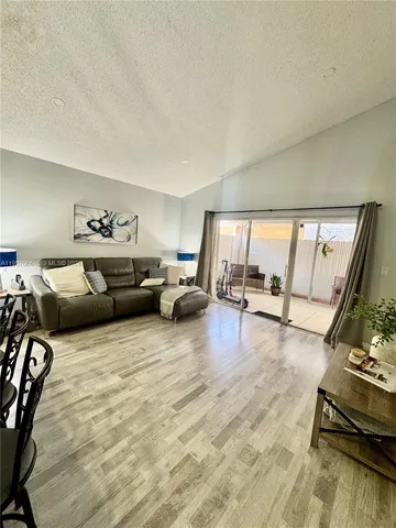 a living room with furniture hard wood floor and floor to ceiling window