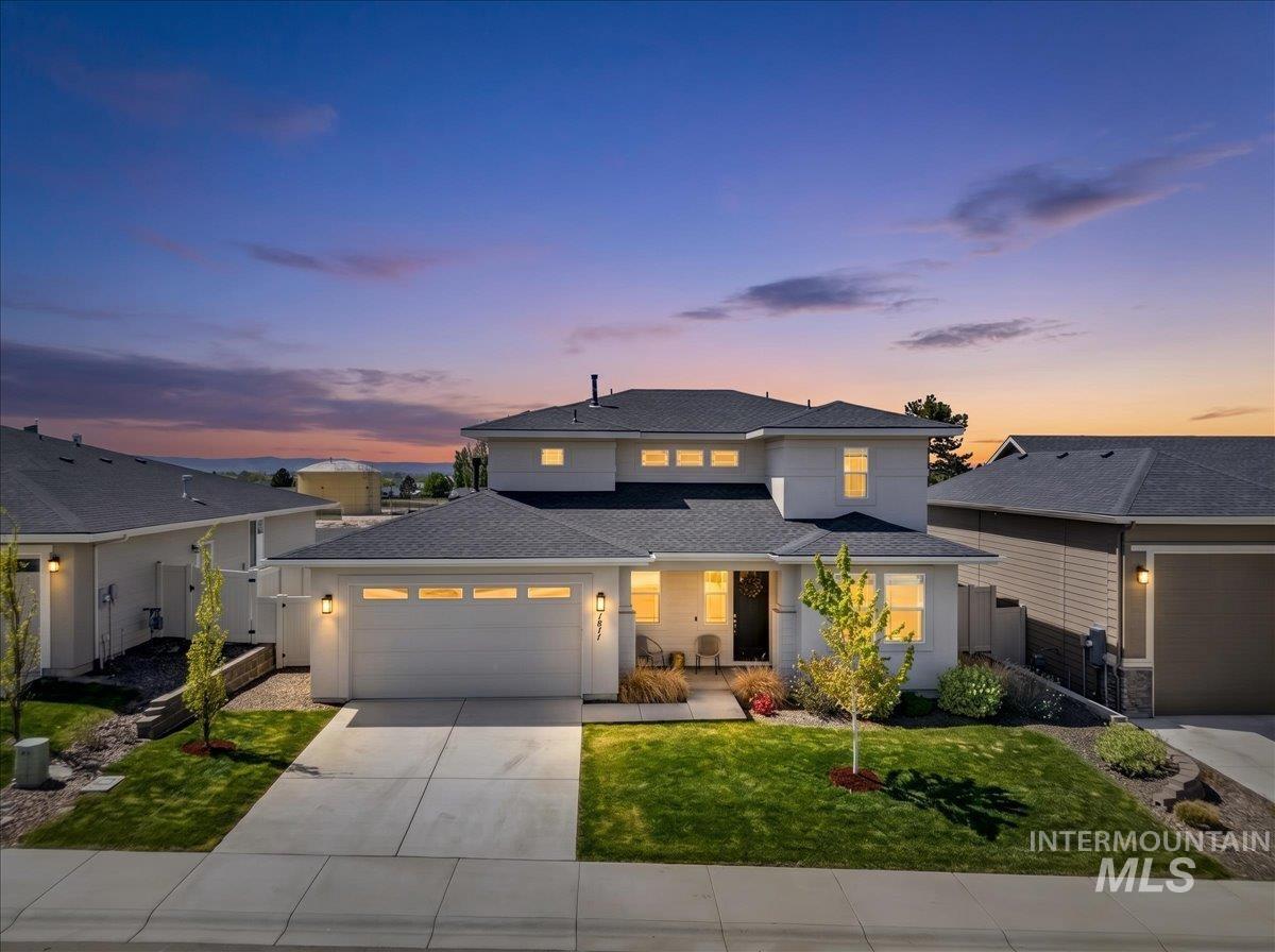 Contemporary white exterior with dark roofline, featuring a two-car garage, mature landscaping, and an inviting front entry