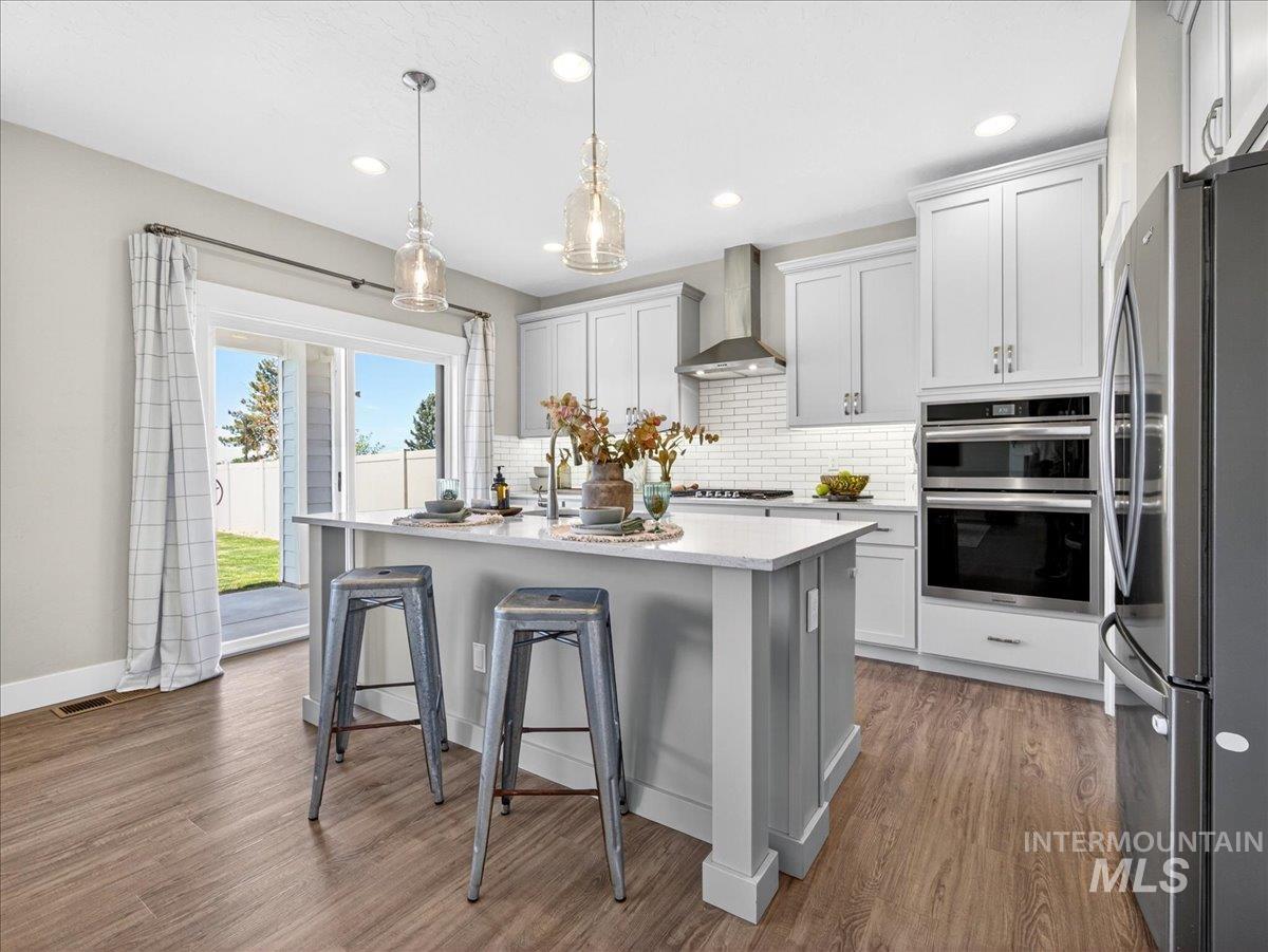 1811 Rome Avenue Emmett, ID 83617 - Photo 14 of 50 Modern kitchen featuring a light gray island with a light-toned countertop, white cabinetry, stainless steel appliances, and wood-finish flooring