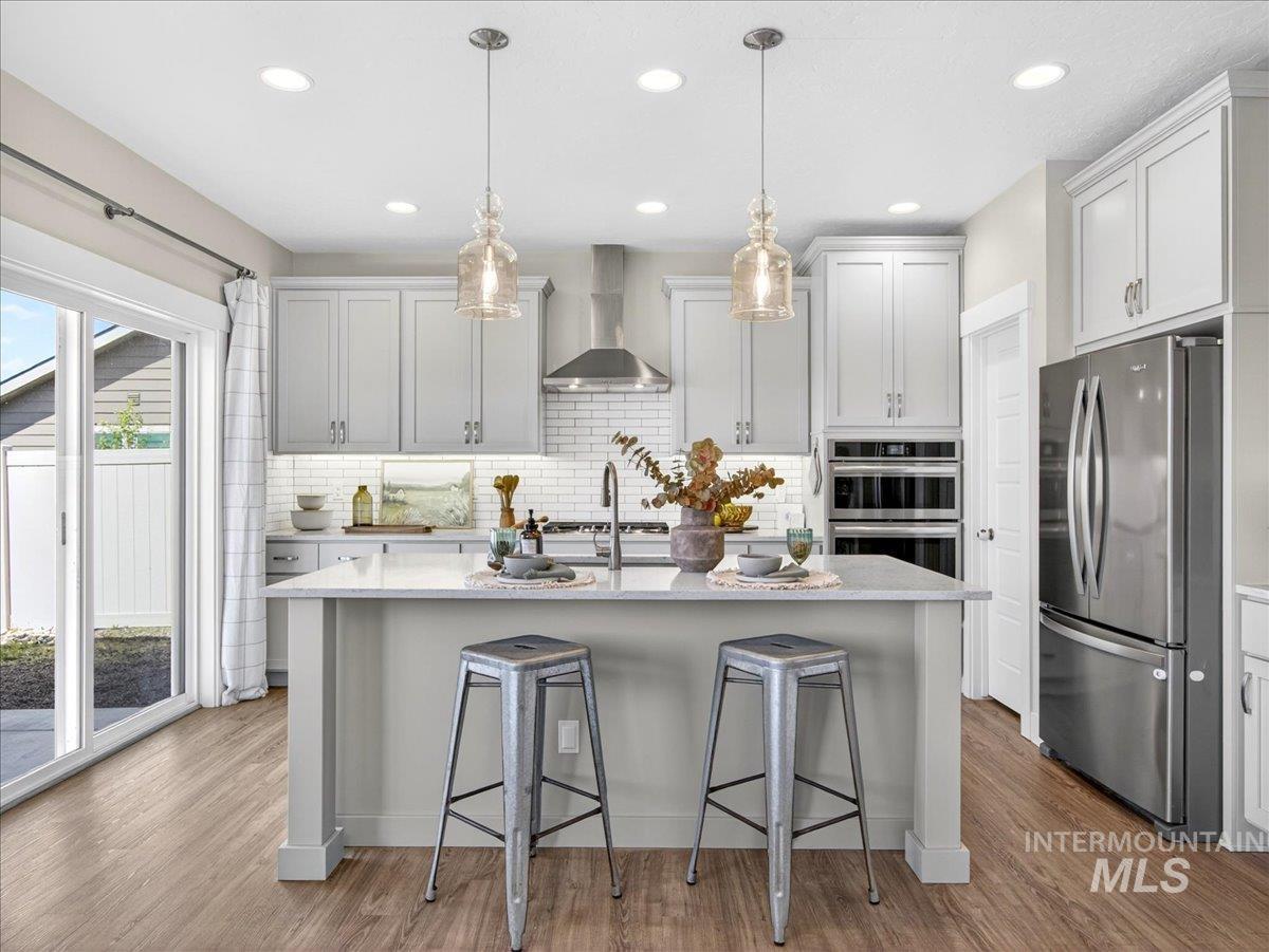 1811 Rome Avenue Emmett, ID 83617 - Photo 16 of 50 Kitchen featuring an island with pendant lighting, wood-finish flooring, stainless steel appliances, and a subway tile backsplash