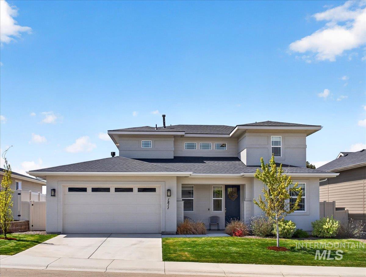1811 Rome Avenue Emmett, ID 83617 - Photo 2 of 50 Contemporary two-story residence featuring a light-toned exterior, dark shingle roofing, an attached two-car garage with transom windows, a concrete driveway, and front landscaping