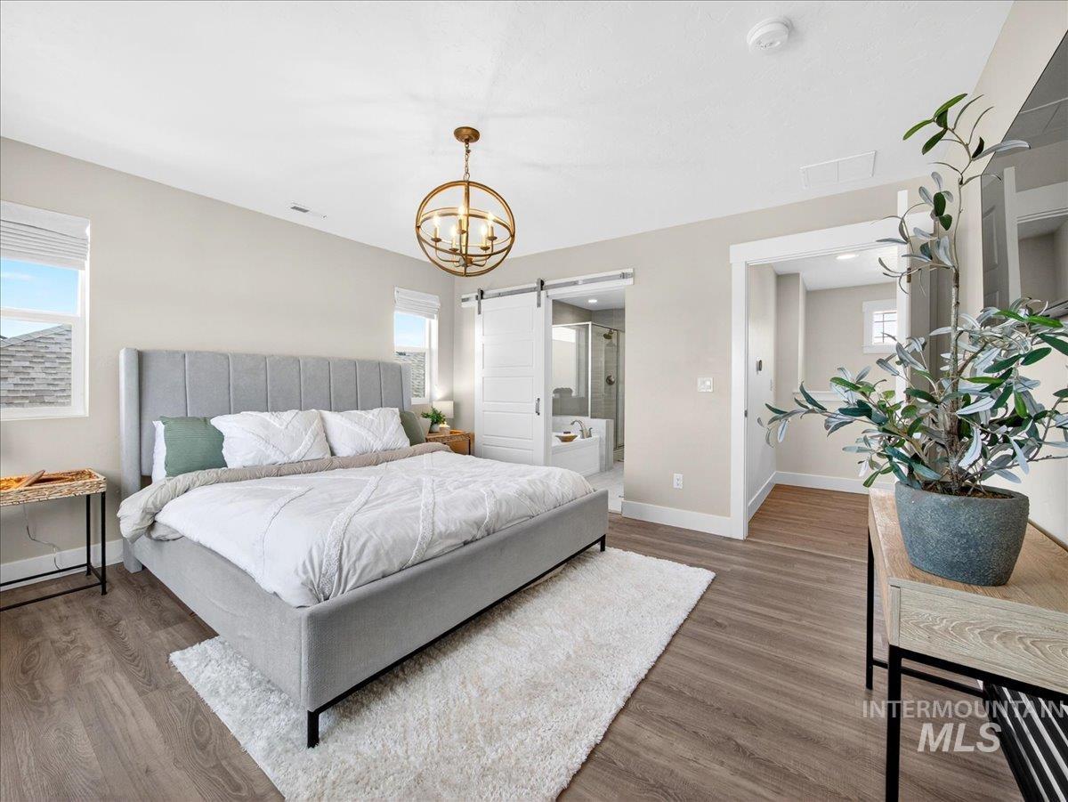 1811 Rome Avenue Emmett, ID 83617 - Photo 27 of 50 Spacious bedroom featuring wood-finish flooring, a contemporary gold-finish chandelier, and ample natural light from multiple windows