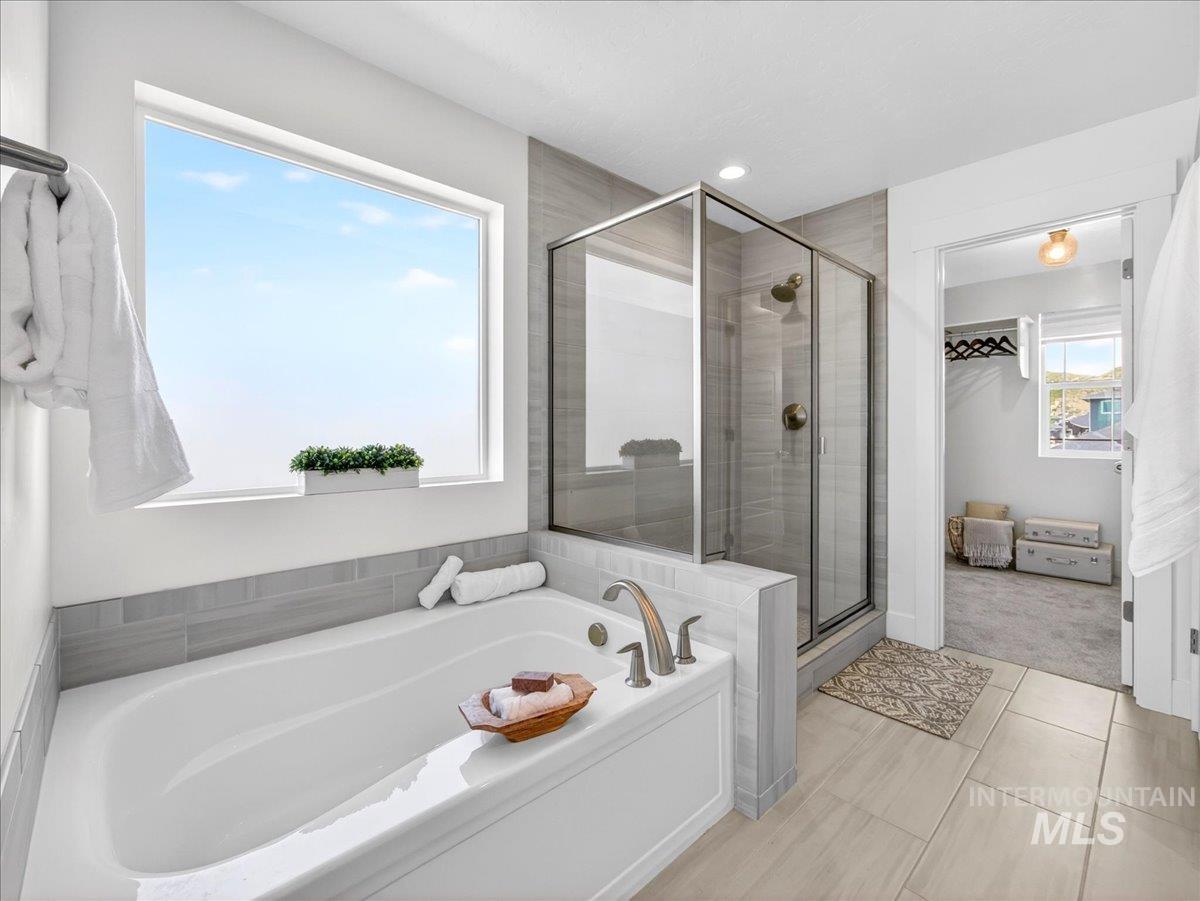 1811 Rome Avenue Emmett, ID 83617 - Photo 31 of 50 Spacious bathroom featuring a white soaking tub, walk-in shower with glass enclosure, light-toned tile flooring, and a large window