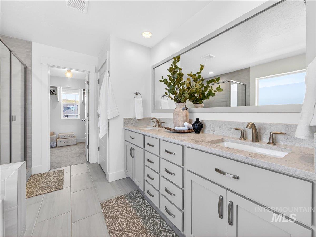 1811 Rome Avenue Emmett, ID 83617 - Photo 33 of 50 Bright bathroom featuring a dual vanity with light-toned countertops and undermount sinks, bronze-finish fixtures, a large frameless mirror, and plank-style tile flooring