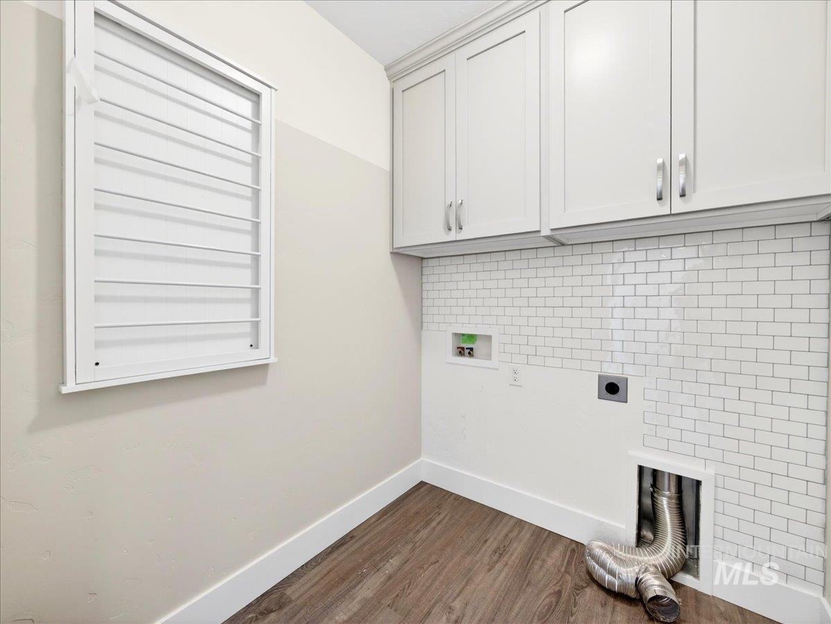 1811 Rome Avenue Emmett, ID 83617 - Photo 40 of 50 Laundry room featuring wood-finish flooring, white subway tile backsplash, and upper cabinetry with crown molding