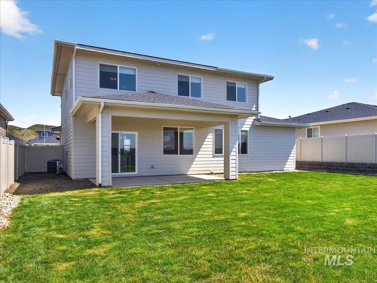 1811 Rome Avenue Emmett, ID 83617 - Photo 42 of 50 Expansive green lawn with a covered concrete patio, light-colored siding, multiple windows, and a sliding glass door
