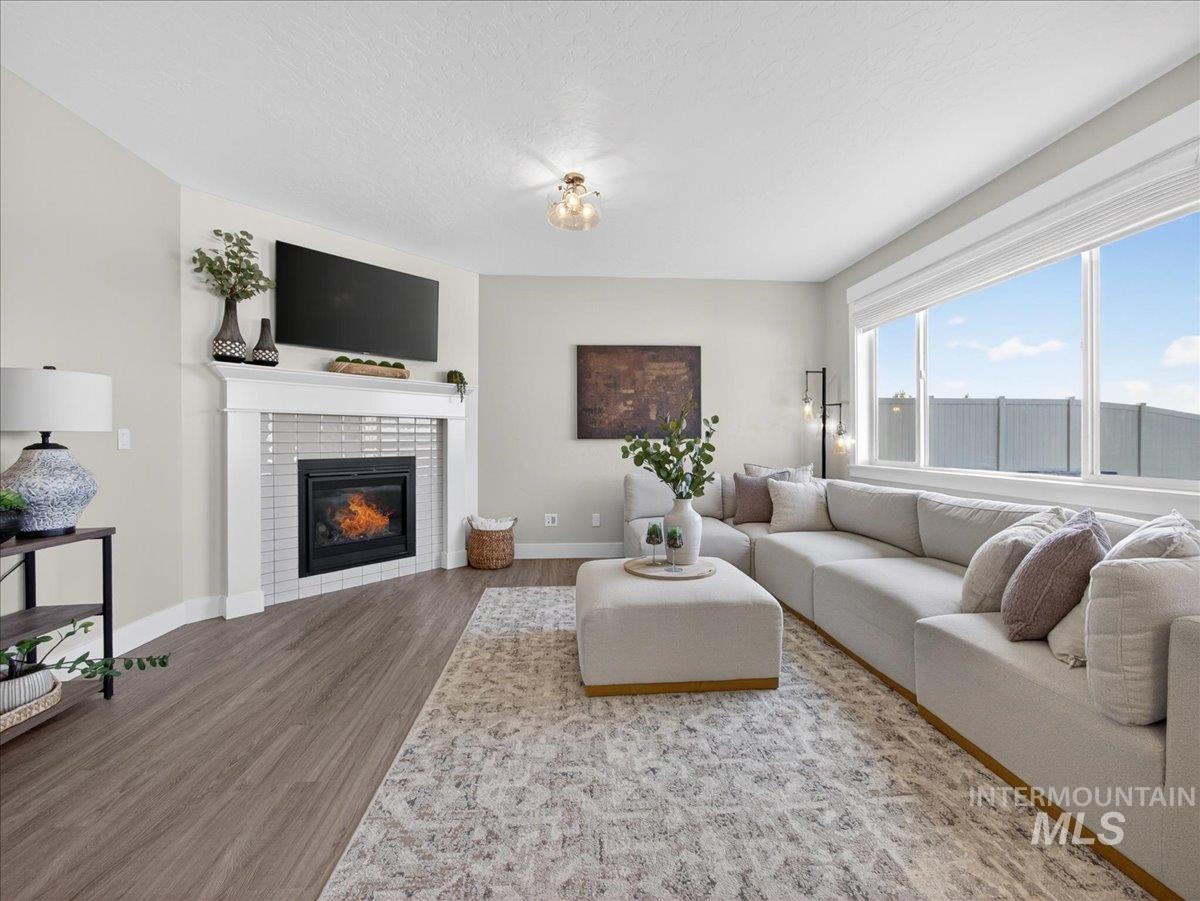 1811 Rome Avenue Emmett, ID 83617 - Photo 8 of 50 Living area featuring wood-finish flooring, a corner fireplace with subway tile surround and white mantel, and large windows