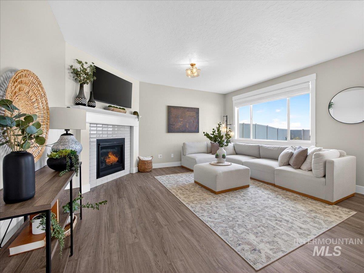 1811 Rome Avenue Emmett, ID 83617 - Photo 10 of 50 Living area featuring wood-finish flooring, a corner fireplace with white tile surround and mantel, and a large window providing ample natural light