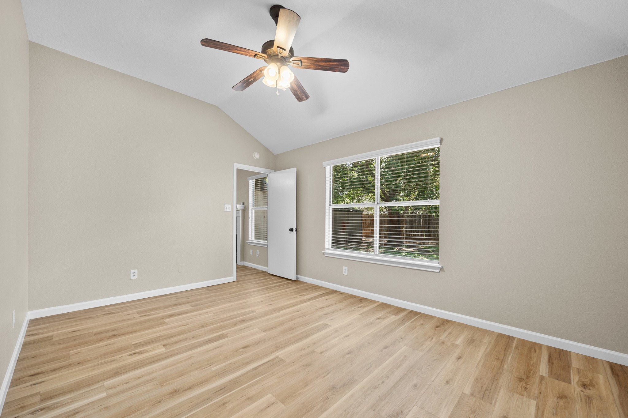 1806 Rusty Nail Loop Round Rock, TX 78681 - Photo 18 of 28 A roomy bedroom features light wood flooring, a vaulted ceiling, and a prominent ceiling fan for comfort.