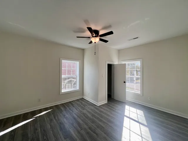 a view of an empty room with a window and wooden floor