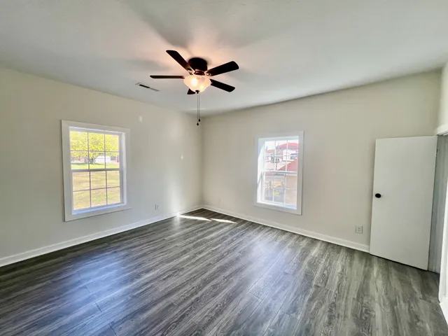a view of an empty room with a window and wooden floor