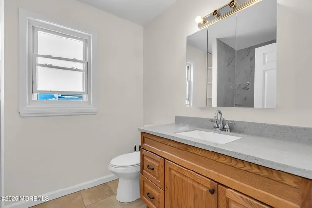 a bathroom with a granite countertop toilet a sink and a mirror