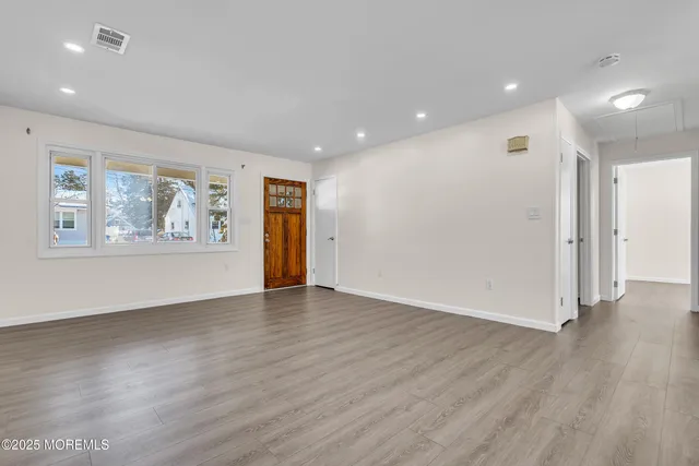 an empty room with wooden floor and window