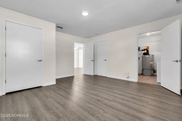 a view of an empty room with wooden floor and closet