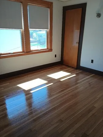 a view of empty room with window and wooden floor
