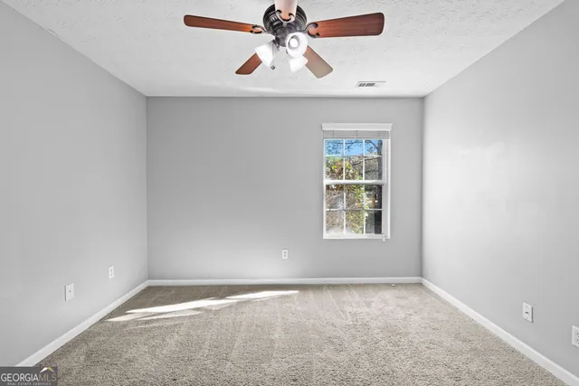 a view of an empty room with window and a kitchen