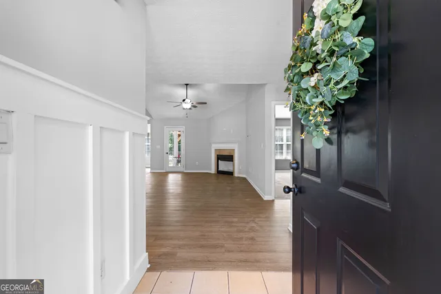 a view of a hallway to a livingroom with wooden floor and a potted plant