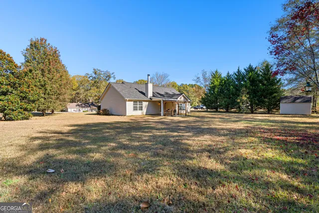 a view of house with yard and trees in the background