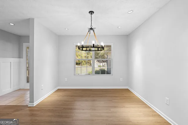 a view of a room with wooden floor chandeliers and kitchen view