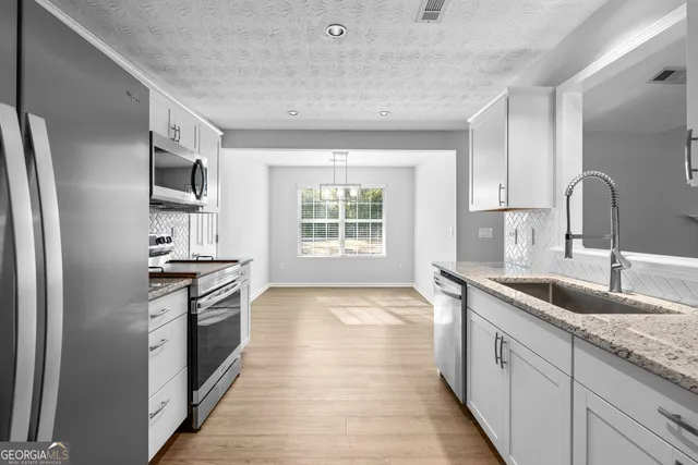 a kitchen with granite countertop stainless steel appliances a sink stove and refrigerator