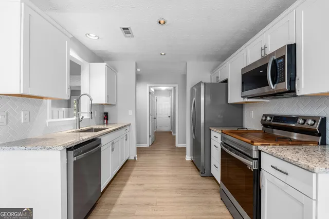 a kitchen with stainless steel appliances granite countertop a stove top oven a sink dishwasher a refrigerator and a microwave oven with wooden floor