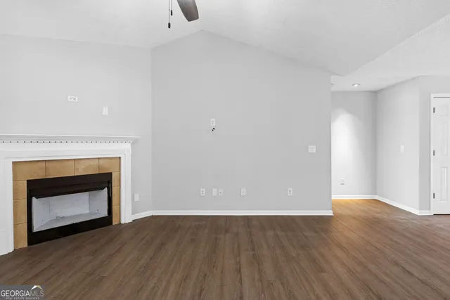 a view of an empty room with wooden floor and a fireplace