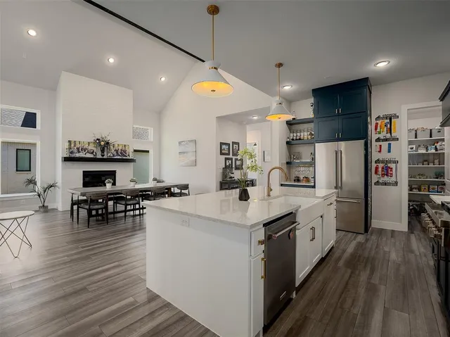 a kitchen with stainless steel appliances kitchen island granite countertop a stove top oven a refrigerator a dining table and chairs with wooden floor