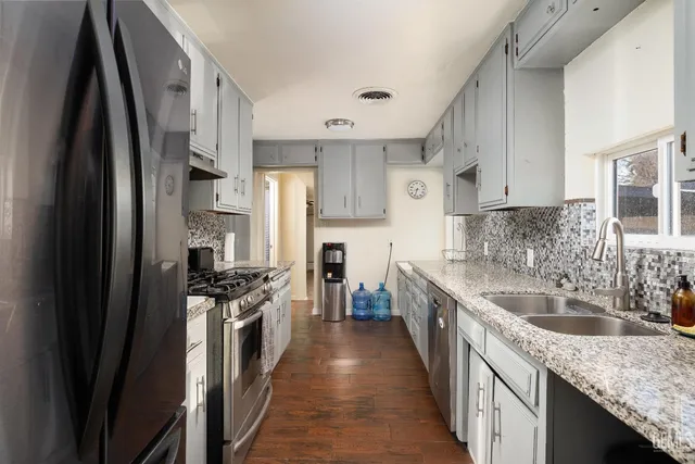 a kitchen with granite countertop a sink stove and refrigerator