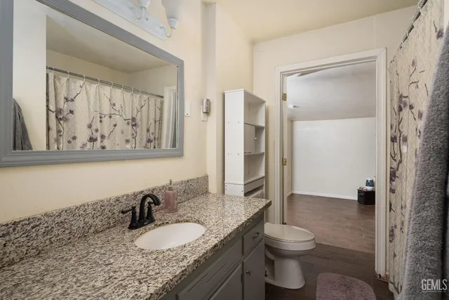a bathroom with a granite countertop toilet sink and mirror