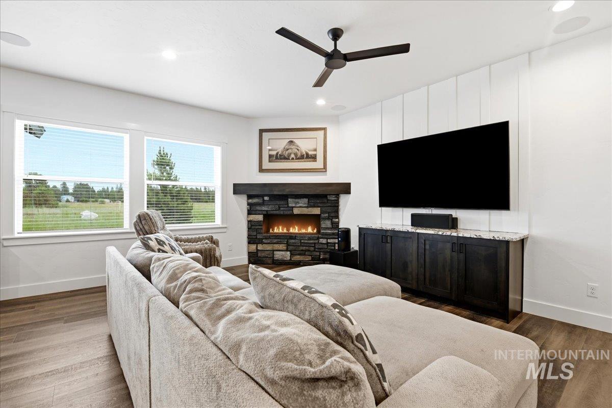 13152 Hawks Bay Road Donnelly, ID 83615 - Photo 4 of 29 Living area featuring a stone-clad fireplace with a dark wood mantel, wood-finish flooring, and white board and batten accent wall