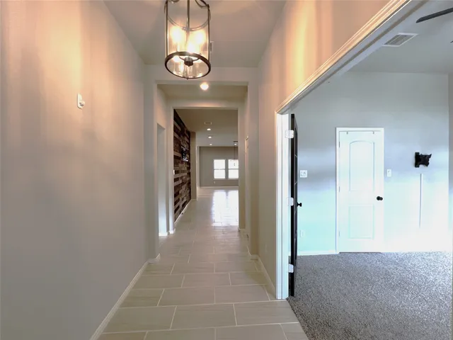 a view of a hallway with wooden floor and chandelier