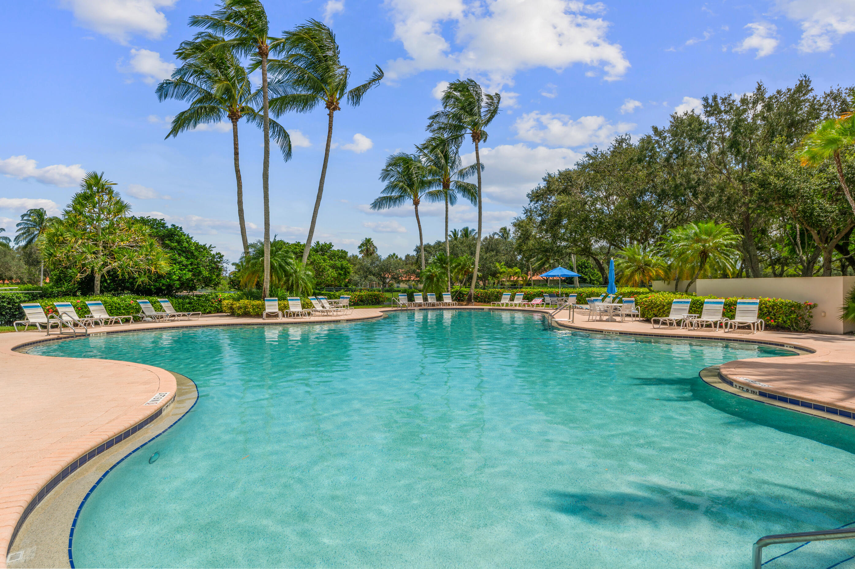 7718 Spring Creek Drive West Palm Beach, FL 33411 - Photo 55 of 72 a view of a swimming pool with a table and chairs