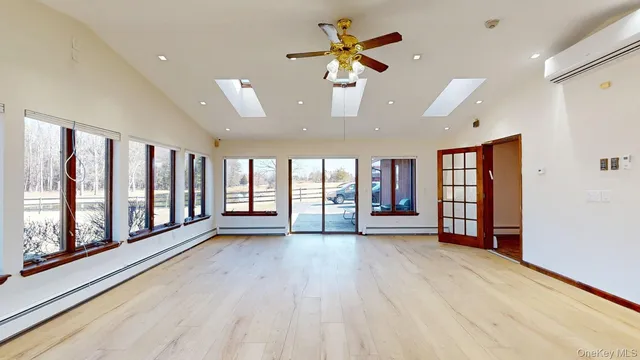 an empty room with a chandelier fan and windows
