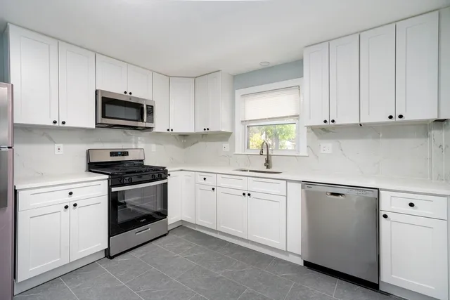 a kitchen with white cabinets and stainless steel appliances