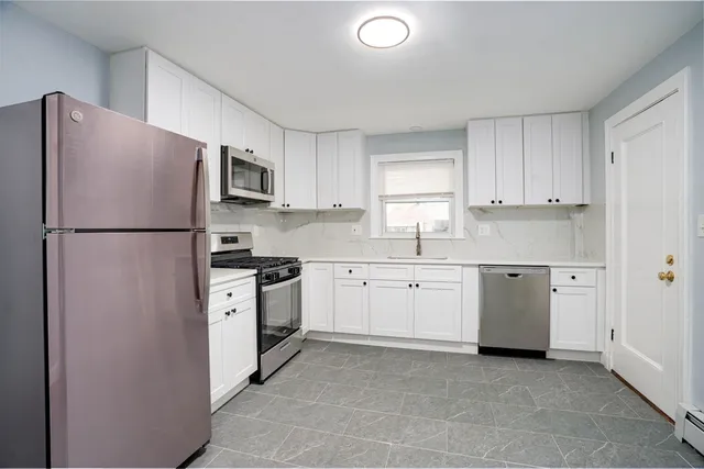 a kitchen with cabinets stainless steel appliances and a window