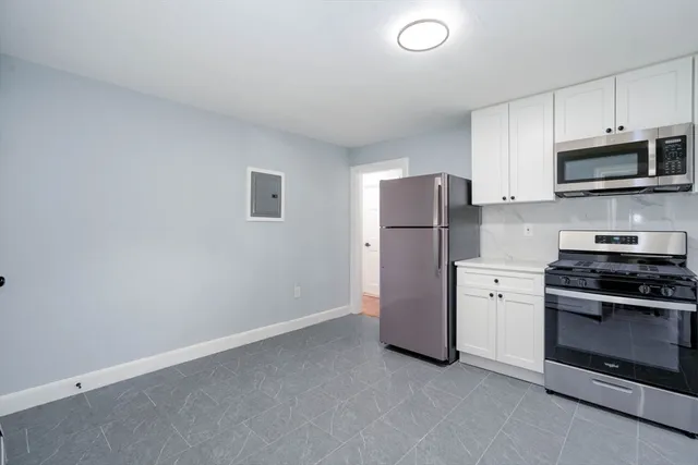 a kitchen with stainless steel appliances white cabinets and a refrigerator