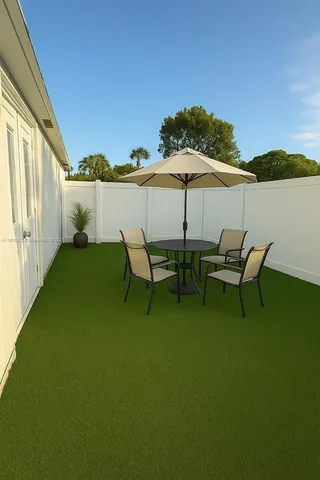a couple of chairs and a table under an umbrella in backyard of house