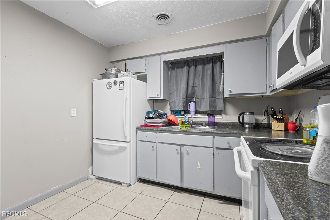 117 Texas Road Lehigh Acres, FL 33936 - Photo 5 of 19 a kitchen with stainless steel appliances a refrigerator sink and cabinets