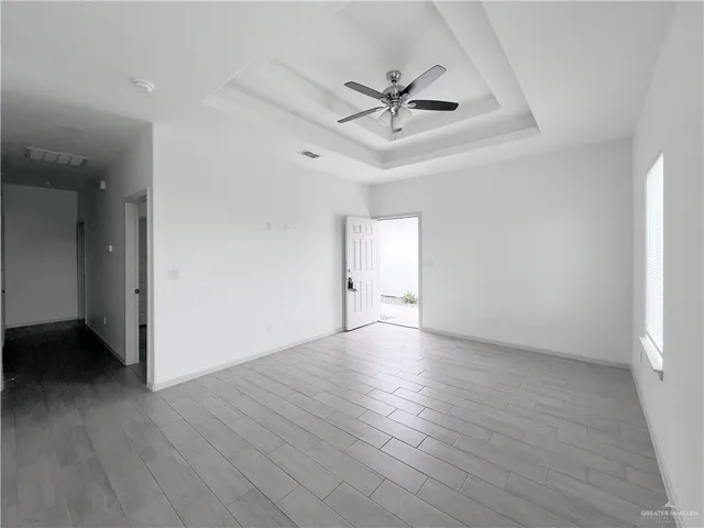 an empty room with wooden floor fan and windows